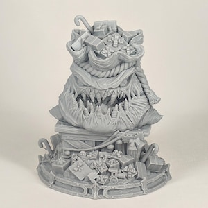 Könnte beinhalten: Eine graue Weihnachtsdekoration mit Monster-Motiv. Die Skulptur zeigt eine große, aufgerissene Kreatur mit einem Sack voller Geschenke. Die Geschenke umfassen verpackte Schachteln und eine Zuckerstange.