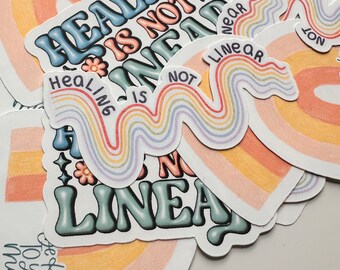 May include: A set of colorful rainbow stickers with the text "Healing is not linear" in a retro font. The stickers feature a rainbow design with a wavy line pattern.