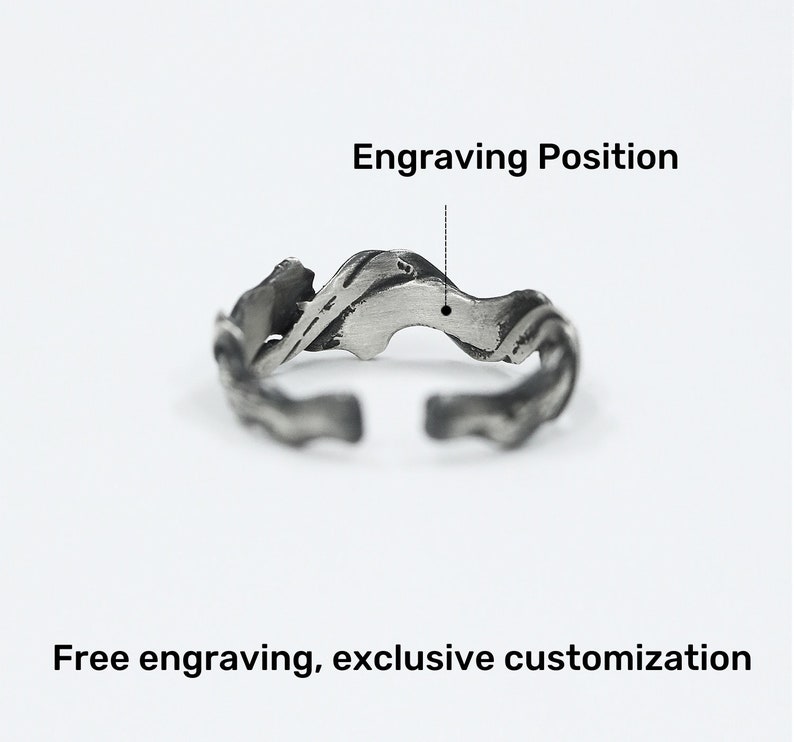 Pu&ograve; includere: Un anello regolabile color argento con un design strutturato e organico. L'anello presenta una forma ondulata e fluida con un'apertura nella parte inferiore. L'immagine include il testo "Engraving Position" e "Free engraving, exclusive customization".