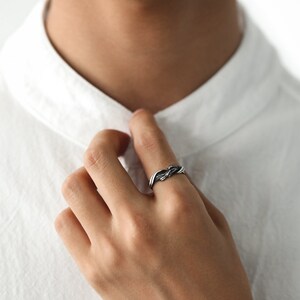Pu&ograve; includere: Un anello argentato con un design intrecciato. L'anello &egrave; indossato su un dito, mettendo in risalto il suo motivo intricato e la lucentezza metallica. Il design dell'anello presenta fili intrecciati, creando un accessorio strutturato ed elegante.