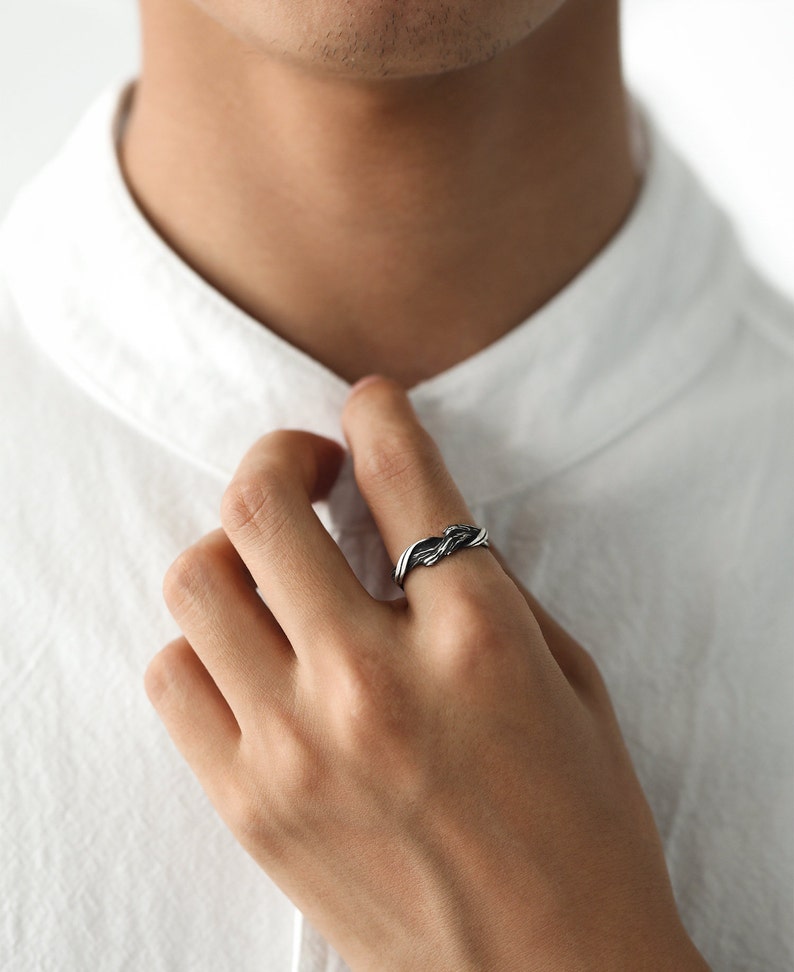 Pu&ograve; includere: Un anello argentato con un design intrecciato. L'anello &egrave; indossato su un dito, mettendo in risalto il suo motivo intricato e la lucentezza metallica. Il design dell'anello presenta fili intrecciati, creando un accessorio strutturato ed elegante.