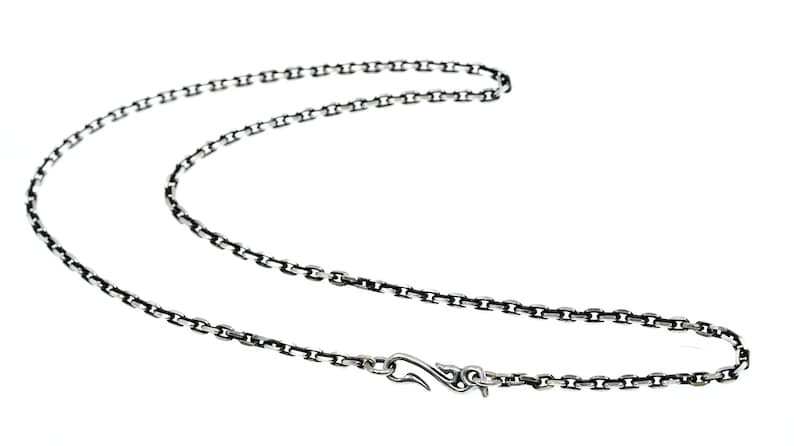Op de afbeelding: Een zilveren ketting met een karabijn sluiting. De ketting is gemaakt van kleine, met elkaar verbonden cirkels.
