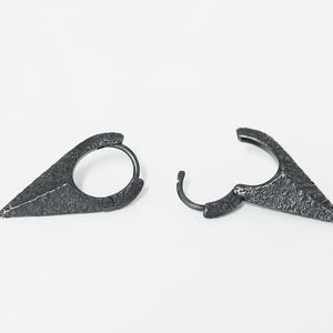 May include: A pair of silver hoop earrings with a pointed, textured design. The earrings are made of metal and have a hammered finish.