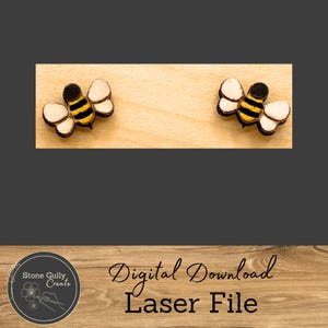 May include: Digital download laser file for two bee designs. The bees are yellow and black with white wings. The design is on a light wood background.