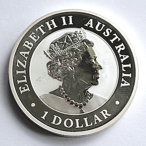 May include: A silver Australian 1 Dollar coin. The coin features a profile of Queen Elizabeth II, with the words "ELIZABETH II AUSTRALIA" and "1 DOLLAR" inscribed around the edge. The coin has a detailed design and a shiny finish.