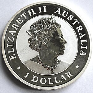 May include: A silver Australian 1 dollar coin. The coin features a profile of Queen Elizabeth II, the words "ELIZABETH II AUSTRALIA" and "1 DOLLAR" are inscribed around the edge. The coin has a detailed design.