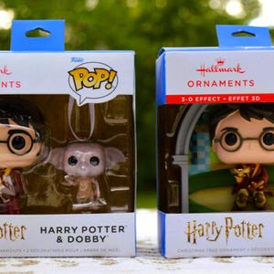 May include: Two Hallmark Pop! Christmas tree ornament boxes featuring Harry Potter characters. The left box contains Harry Potter and Dobby figures. The right box features a Harry Potter figure with a 3-D effect background and a Walmart exclusive label.