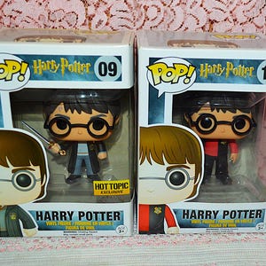 May include: Two Funko Pop Harry Potter vinyl figures in their original boxes. The left box is number 09, featuring Harry with a sword and a Hot Topic Exclusive sticker. The right box is number 10, featuring Harry in a red and black jacket.