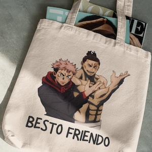 May include: A beige tote bag with a print of two anime characters. The characters are a muscular man with a shaved head and a man with pink hair. The text "BESTO FRIENDO" is printed on the bag.