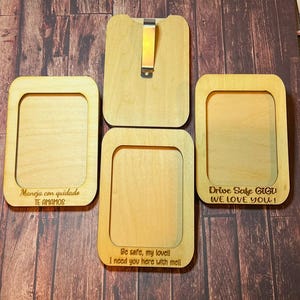 May include: Four wooden picture frames with engraved messages. The frames are light brown and have a rectangular shape. The messages are "Maneja con cuidado TE AMAMOS", "Be safe, my lovel!! I need you here with me!!", "Drive Safe GiGi! WE LOVE YOU!" and a blank frame.