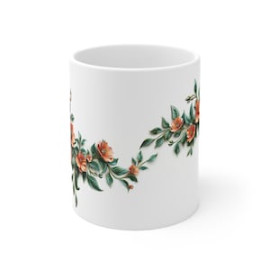 Könnte beinhalten: Weiße Keramiktasse mit einem Blumendesign mit orangefarbenen Blüten und grünen Blättern um die untere Hälfte der Tasse.