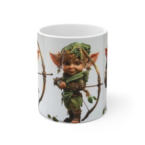 May include: White ceramic mug featuring a colourful illustration of a small, green-skinned creature with large ears, holding a bow and arrow. The creature is wearing a green hat and a green tunic.