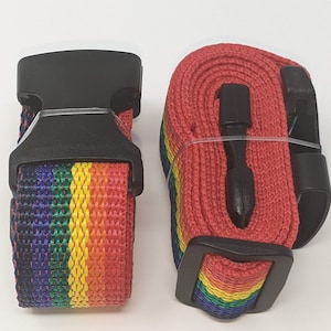 May include: Two rainbow luggage straps with black buckles. The straps are made of woven fabric with red, orange, yellow, green, blue, and purple stripes.