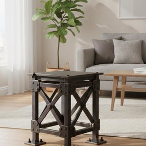 Puede incluir: Una mesa auxiliar de estilo industrial, de color marrón oscuro, con una parte superior cuadrada y una base con refuerzos cruzados. La mesa mide aproximadamente 51 cm de altura y presenta pernos y placas metálicas visibles. El diseño sugiere una estética robusta y rústica.