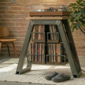 Könnte beinhalten: Ein moderner Plattenspieler steht auf einem Metall- und Holzständer mit integrierter Schallplattenaufbewahrung. Der Ständer hat ein dreieckiges Gestell und mehrere Regale mit Vinylplatten. Ein Paar graue Hausschuhe liegt auf dem Teppich vor dem Ständer.