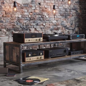 Può includere: Un sistema audio ad alta fedeltà con due altoparlanti in legno su supporti metallici, una lunga console multimediale in legno con telaio in metallo, un giradischi e diversi componenti audio elettronici con manopole dorate.