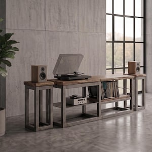 Peut inclure: Un meuble multimédia avec un plateau en bois et une structure en métal gris, comprenant une platine vinyle sur la surface centrale, deux enceintes sur des supports latéraux et des étagères inférieures contenant des appareils et des disques.