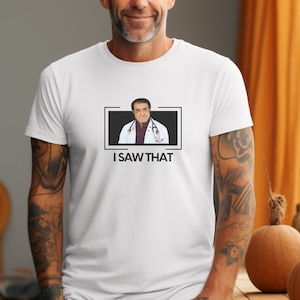 Może przedstawiać: Biała koszulka z czarno-białym obrazkiem mężczyzny w białym fartuchu lekarskim i stetoskopem. Pod obrazkiem znajduje się napis "I SAW THAT".