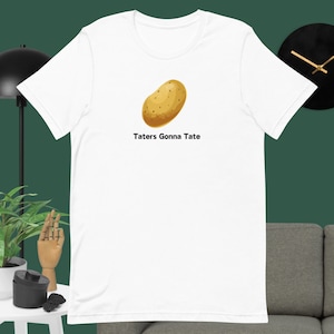 Pode incluir: Camiseta branca com uma ilustração de batata marrom e o texto "Taters Gonna Tate" impresso na frente.