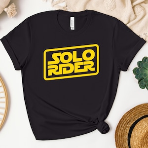 May include: Black t-shirt with a yellow graphic that says "SOLO RIDER" in a Star Wars-inspired font.