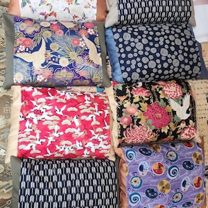 May include: A collection of decorative throw pillows with various patterns. Pillows feature butterfly, floral, and geometric designs in colors like blue, red, and purple. Some pillows have a beige or brown border.
