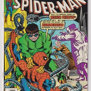 May include: The Amazing Spider-Man comic book issue 158, dated July, featuring a cover illustration of Spider-Man being restrained by Doctor Octopus's mechanical tentacles, with Aunt May and a figure in a purple coat visible in the background.