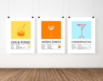 May include: Three framed cocktail recipe prints. The first features a Gin & Tonic illustration on a yellow background. The second showcases an Aperol Spritz on an orange background. The third displays a Cosmopolitan on a light blue background.
