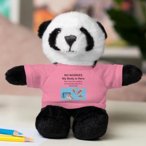 May include: A black and white panda plush toy wearing a pink shirt with the text "NO WORRIES My Body is Here But I Think the Goldfish are Using My Brain for a Soccer Ball" and a picture of goldfish playing soccer.