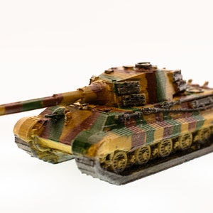 Peut inclure: Maquette détaillée d'un char militaire, avec un motif de camouflage marron, vert et jaune. Le char a un long canon et des chenilles visibles, sur fond blanc. Il s'agit d'un objet de collection.