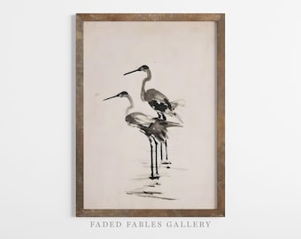 May include: A framed black and white ink painting of two birds standing in a row. The birds are stylised and have long legs and beaks. The background is a light beige colour. The frame is a light brown wood.