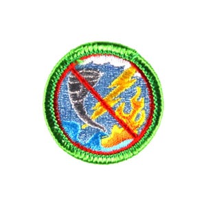 May include: A round patch with a green border, featuring a blue background with a tornado, lightning bolt, and flames, all crossed out with a red line. The patch is likely for a scout or similar organization.