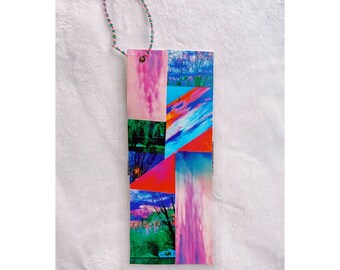 May include: A colorful bookmark with a collage of images of clouds and sky. The bookmark is attached to a beaded string with a key charm.