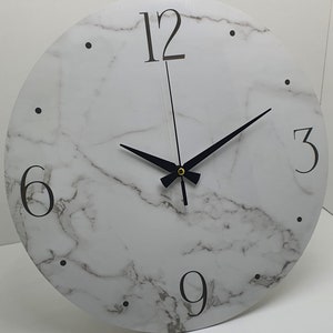 May include: White round clock with black hands and black Roman numeral markings on a marble-patterned background.