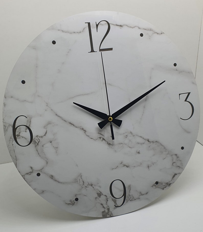 May include: White round clock with black hands and black Roman numeral markings on a marble-patterned background.