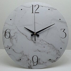May include: White round clock with black hands and black numbers on a marble-patterned face. The numbers 12, 6, 3, and 9 are visible.