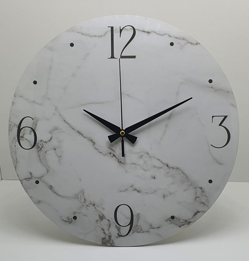 May include: A white round clock with black hands and black numbers on a marble-patterned face. The numbers 12, 6, 3, and 9 are visible.