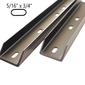May include: Two dark grey metal U-channel brackets featuring a series of evenly spaced oval mounting holes. The text 5/16" x 3/4" is printed above a small oval icon, indicating the specific dimensions of the mounting slots on these components.