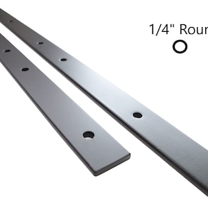 May include: Two 1/4 inch round metal rods with holes drilled along their length.  The rods are silver in color and appear to be made of steel.