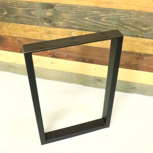 Op de afbeelding: Zwarte metalen tafelpoot met een rechthoekig frame. De poot is gemaakt van stevig metaal en heeft een zwarte afwerking.