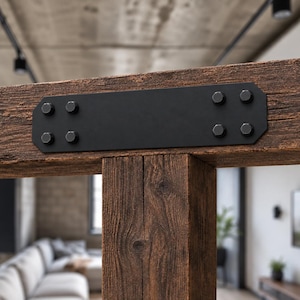 May include: A rectangular black metal plate secured with eight hexagonal bolts, connecting two dark brown textured wooden beams. The metal plate features clipped corners and a smooth matte finish, providing a structural joint for the timber.