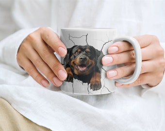 May include: White ceramic mug with a Rottweiler dog breaking through the surface. The dog is black and tan with a white chest and paws.