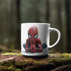 K&ouml;nnte beinhalten: Wei&szlig;e Keramiktasse mit einer detaillierten Illustration von Spider-Man in meditativer Pose. Der Superheld ist in seinem klassischen rot-blauen Anzug dargestellt, die H&auml;nde vor sich gefaltet. Die Tasse hat einen Standardgriff.