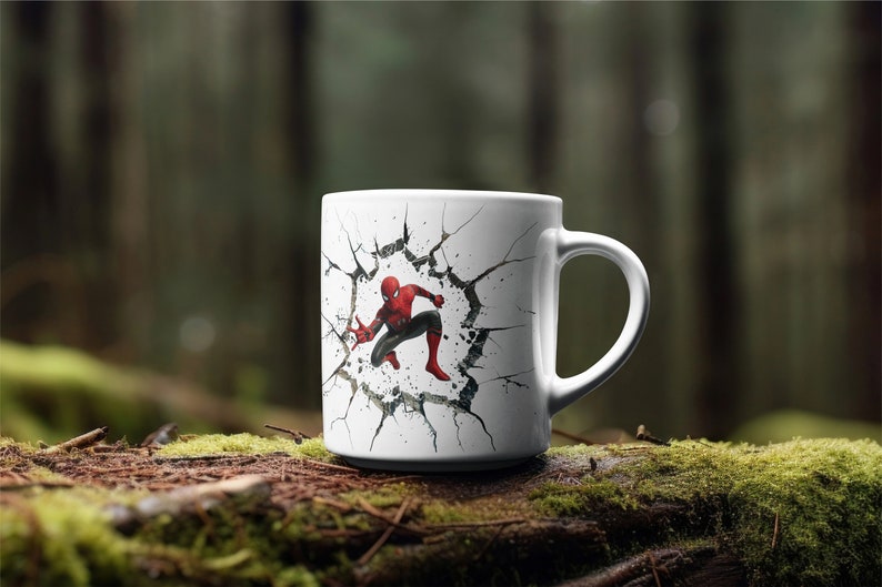 Puede incluir: Taza de cer&aacute;mica blanca con un gr&aacute;fico de Spiderman rompiendo una pared agrietada. La taza tiene un asa negra.