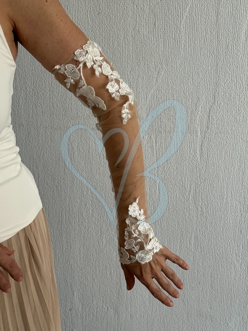 May include: White lace elbow-length gloves with floral embroidery on a sheer mesh fabric.