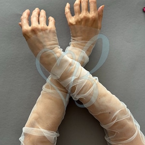 K&ouml;nnte beinhalten: Ein Paar durchsichtige wei&szlig;e T&uuml;llhandschuhe, die bis zum Ellbogen reichen. Die Handschuhe sind aus einem zarten, leichten Stoff gefertigt und haben einen leicht gerafften Look.