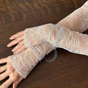 May include: Delicate white lace arm warmers with a floral pattern. The arm warmers are made of a sheer, lightweight fabric. The lace design adds a touch of elegance. Perfect for weddings, parties, or special occasions.