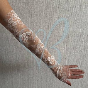 K&ouml;nnte beinhalten: Wei&szlig;e Spitzengloves mit floralem Muster. Die Handschuhe reichen von den Fingerspitzen bis zum Oberarm. Die Spitze ist detailliert und zart, wodurch ein romantischer und eleganter Look entsteht. Perfekt f&uuml;r Hochzeiten oder besondere Anl&auml;sse.