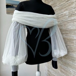 May include: White off-the-shoulder top with sheer, puffed sleeves. The top is made of a lightweight fabric and has a relaxed fit.