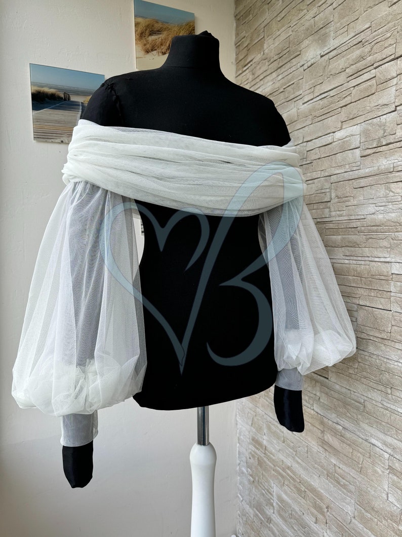 May include: White off-the-shoulder top with sheer, puffed sleeves. The top is made of a lightweight fabric and has a relaxed fit.