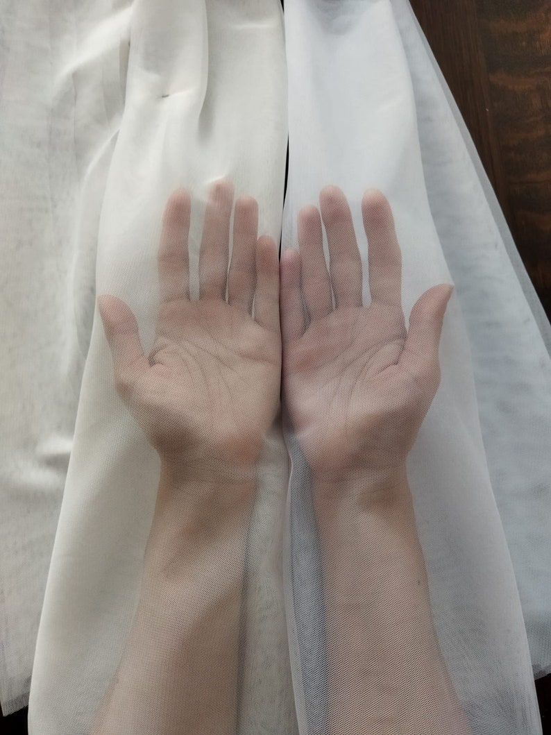 K&ouml;nnte beinhalten: Zwei H&auml;nde sind mit gespreizten Fingern zu sehen, die durch einen durchsichtigen wei&szlig;en Stoff greifen. Der Stoff ist durchscheinend, sodass die H&auml;nde durch ihn hindurch zu sehen sind.